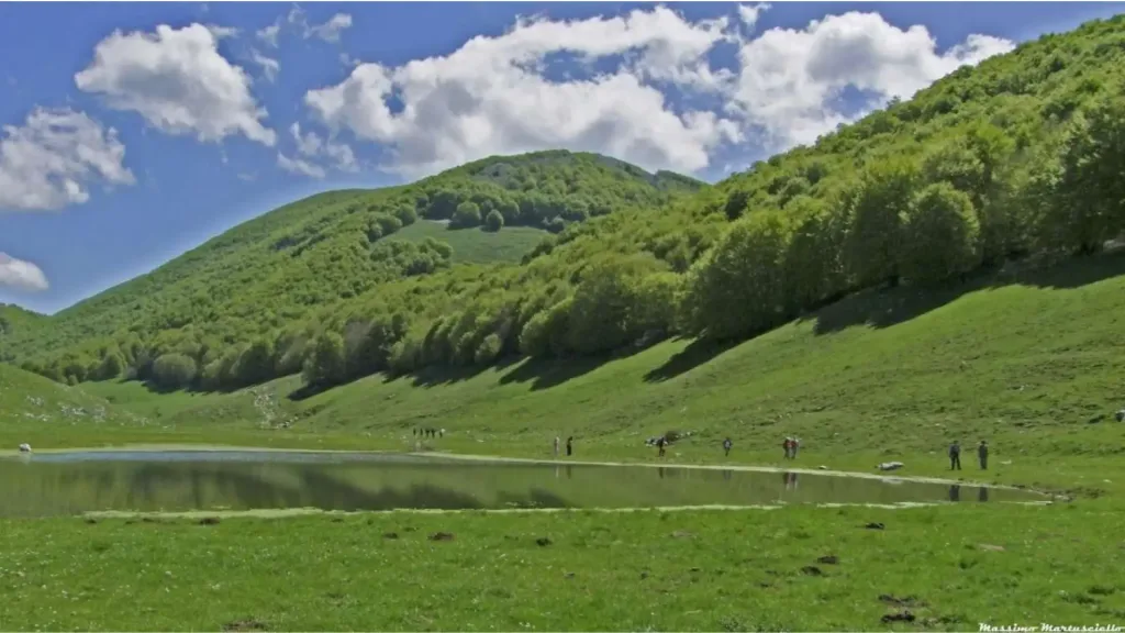 Il laghetto di Campo Figliolo circondato da prati verdi e fitti boschi sulle pendici delle montagne del Matese.