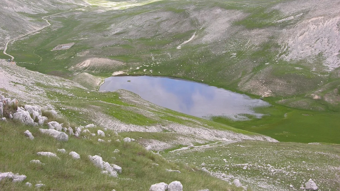 Scorcio panoramico ad alta quota del Lago Pantaniello incastonato nella conca glaciale dell'Appennino abruzzese sotto le vette del gruppo del Monte Greco.